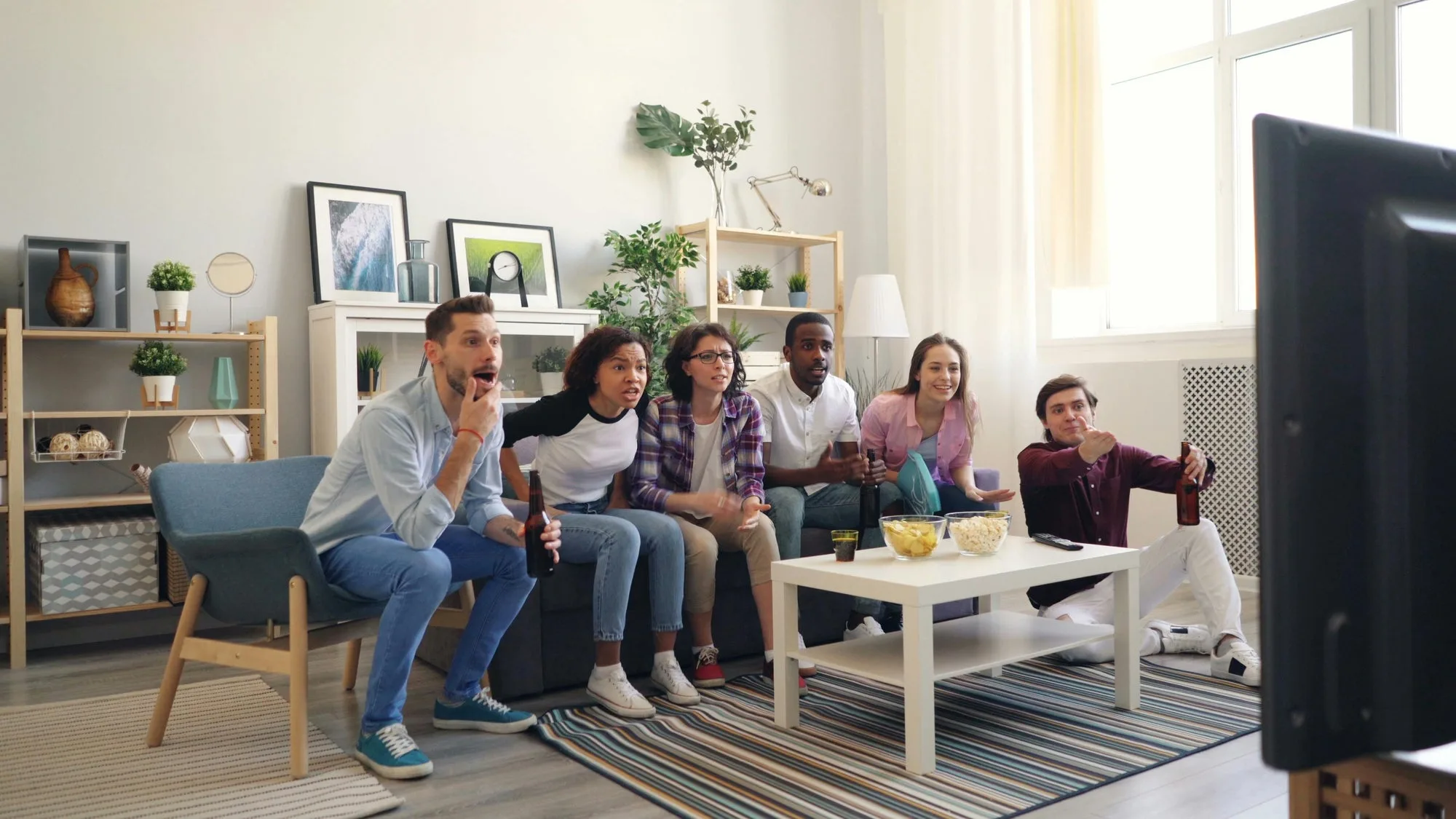 A group of friends relaxing together in a living room, drinks in hand